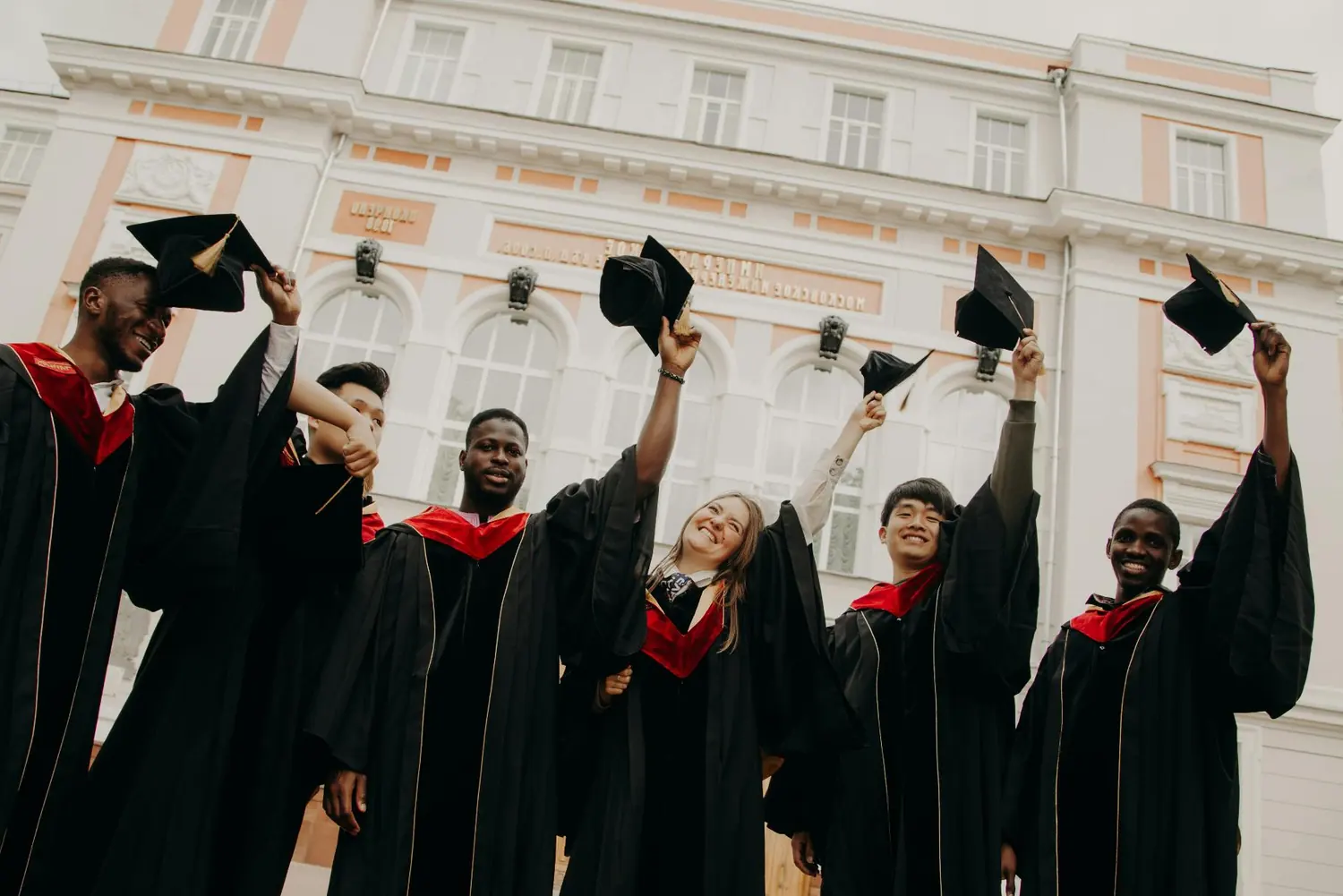 Group of graduates tossing their caps in the air outside a university building