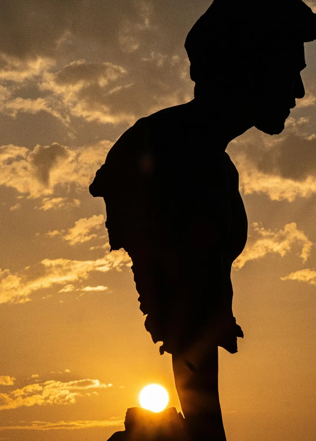 Silhouette of a graduate against a golden sunset sky