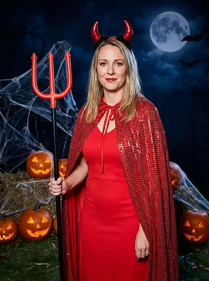 Woman in a glossy red devil cape with horns and a trident against a moonlit pumpkin patch, generated by the Halloween photo pack